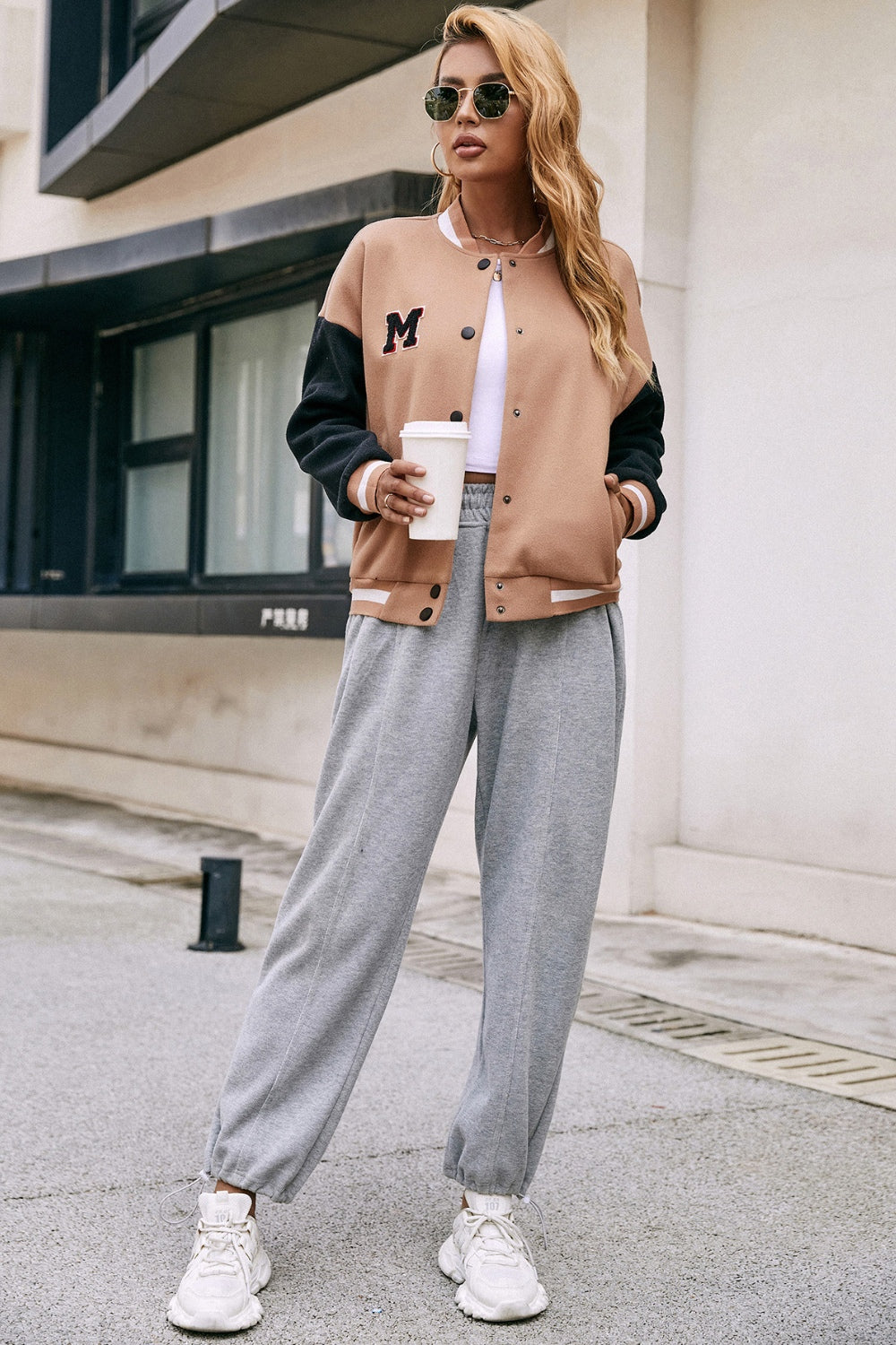 Camel bomber jacket with black sleeves, white trim, and an embroidered M patch.