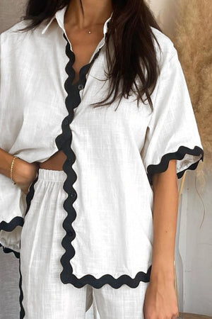 White linen co-ord set with black scalloped trim on shirt and shorts.