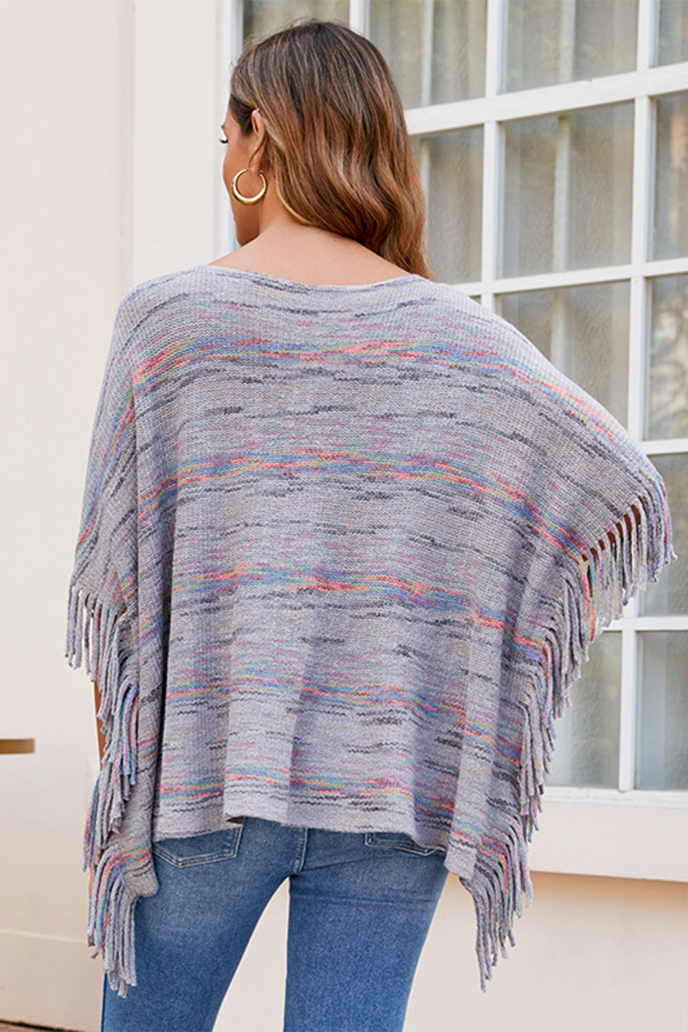 Multicolor knit poncho with fringe detail, crew neck, and relaxed fit.