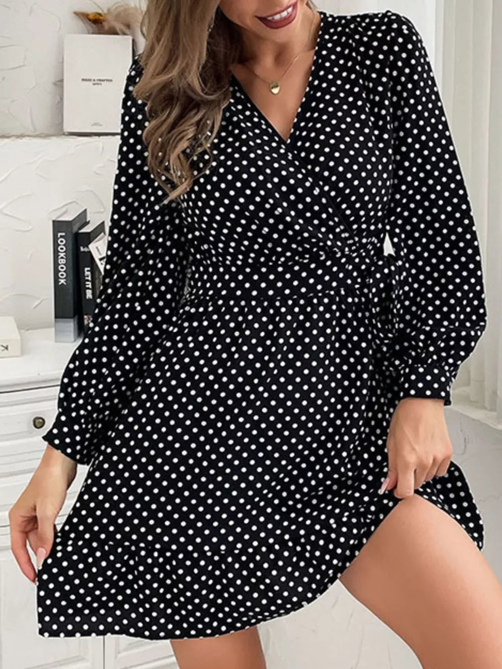 Black polka dot mini dress with V-neck, balloon sleeves, and ruffled hem.