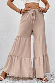 Tiered ruffle palazzo trousers in tan with a drawstring waist and textured fabric.