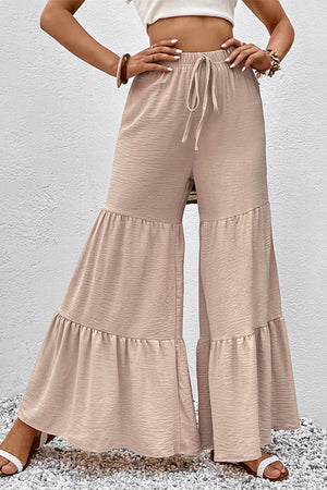 Tiered ruffle palazzo trousers in tan with a drawstring waist and textured fabric.