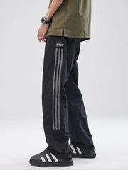 Black drawstring sweatpants with side stripe detail and logo patch