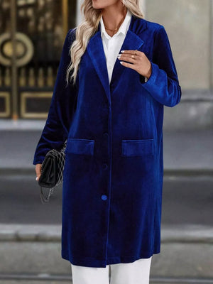 Longline trench coat in deep blue velvet with lapel collar, button front, and flap pockets.