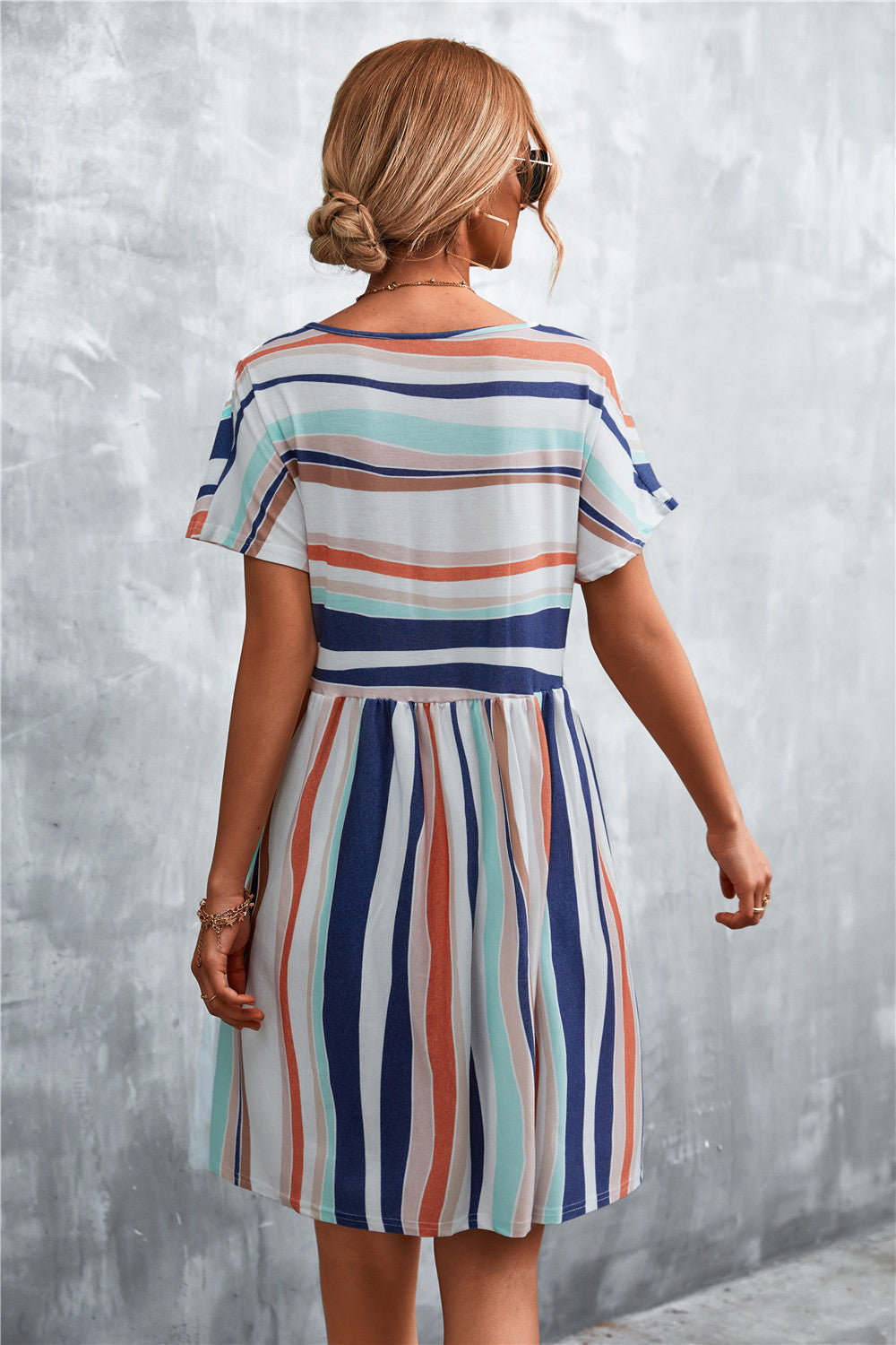 Striped trapeze dress with short sleeves and a gathered waist, featuring horizontal and vertical stripes in coral, navy, and
