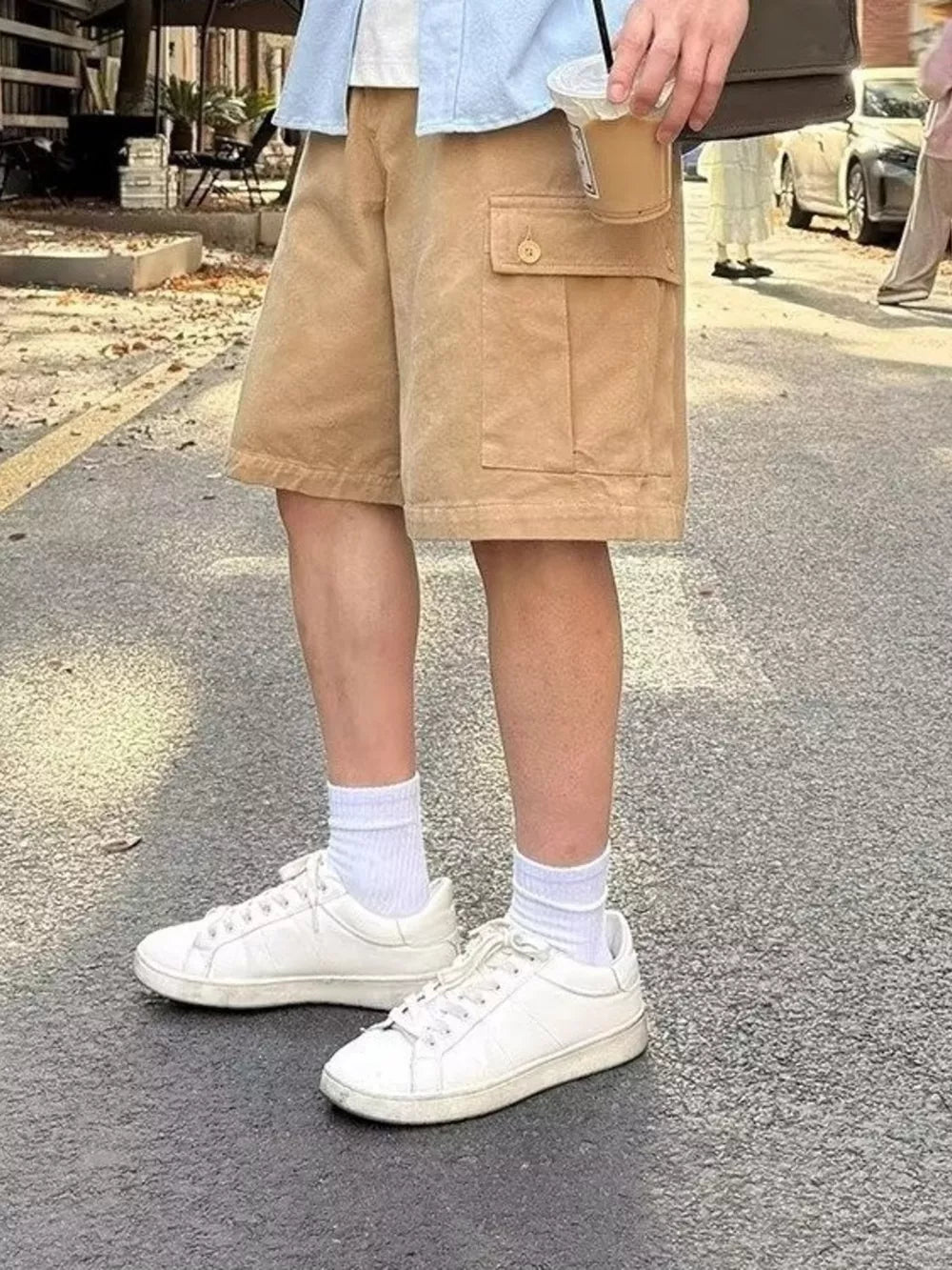 Camel relaxed fit cargo shorts with buttoned flap pockets and above-knee length.