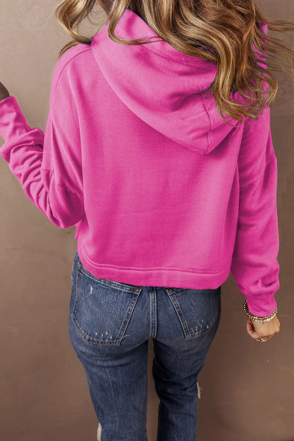 Hot Pink cropped hoodie with hood and long sleeves, styled with jeans.
