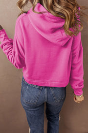 Hot Pink cropped hoodie with hood and long sleeves, styled with jeans.