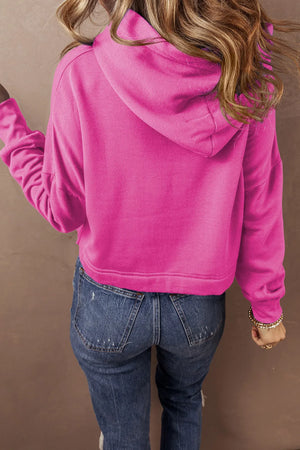 Hot Pink cropped hoodie with hood and long sleeves, styled with jeans.