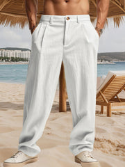 White relaxed fit sweatpants with pleats and a button closure, styled casually.