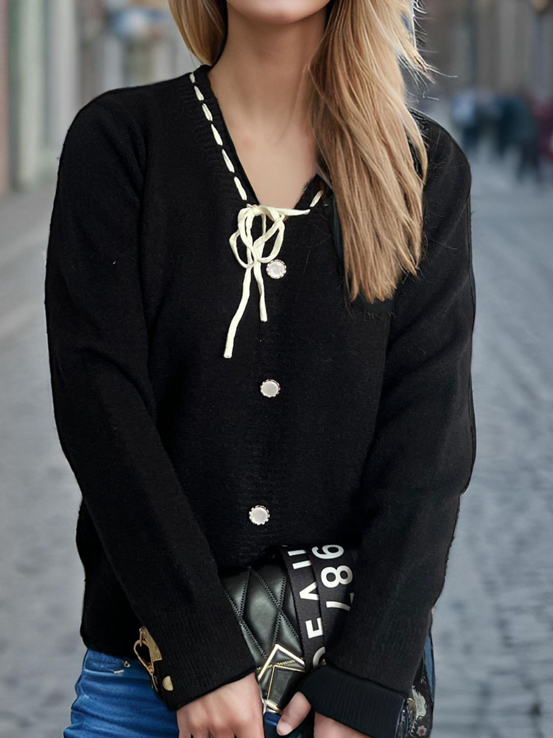 Black knit cardigan with white ribbon trim, bow detail, and pearl buttons.