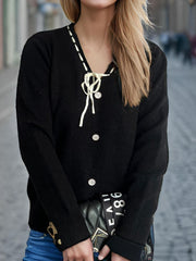 Black knit cardigan with white ribbon trim, bow detail, and pearl buttons.