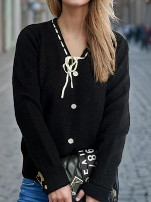 Black knit cardigan with white ribbon trim, bow detail, and pearl buttons.