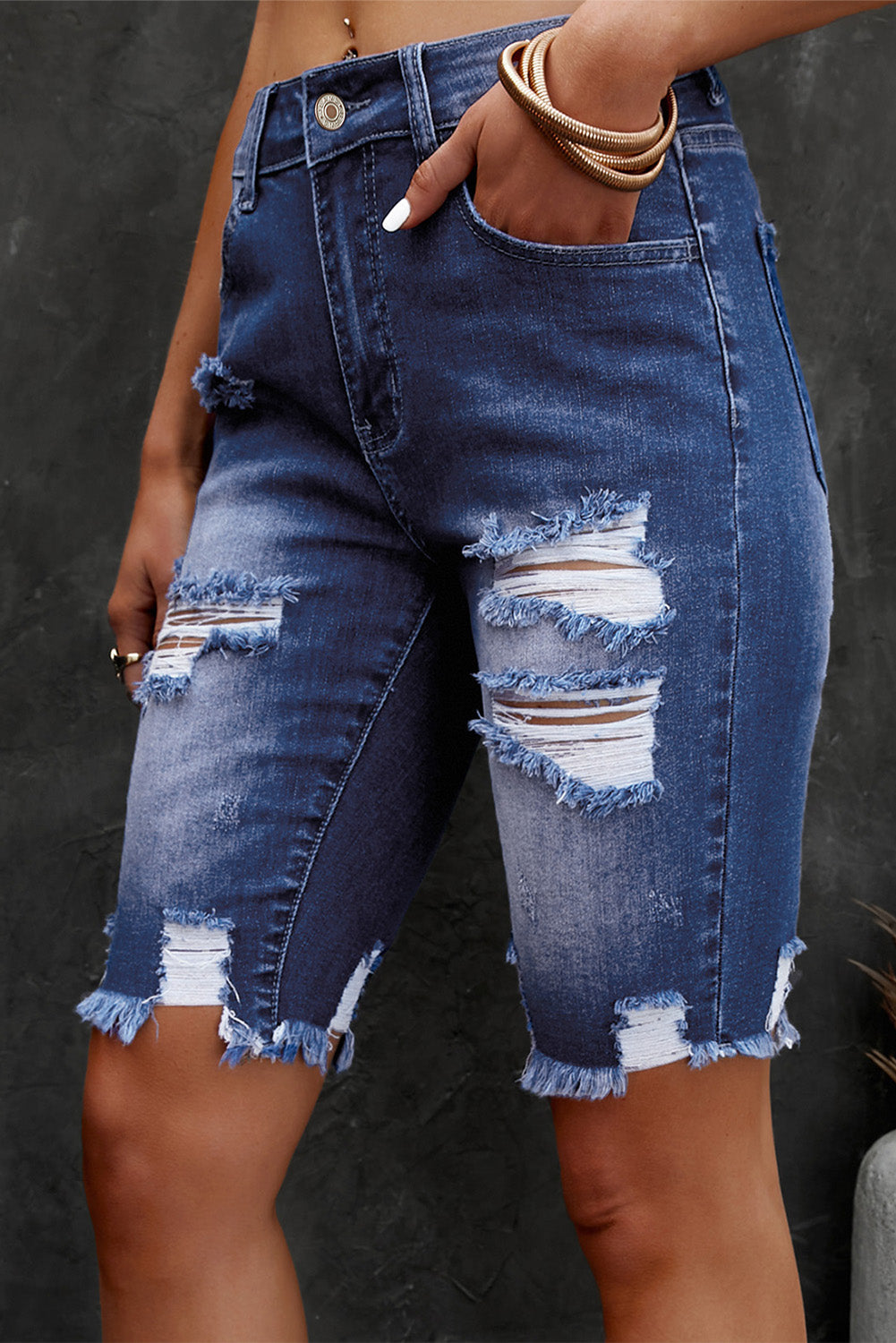 Ripped knee denim bermuda shorts in medium wash with frayed hem and distressed details.