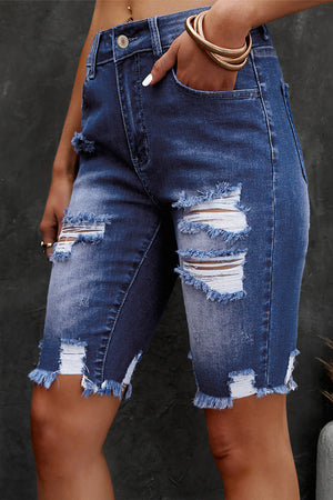 Ripped knee denim bermuda shorts in medium wash with frayed hem and distressed details.