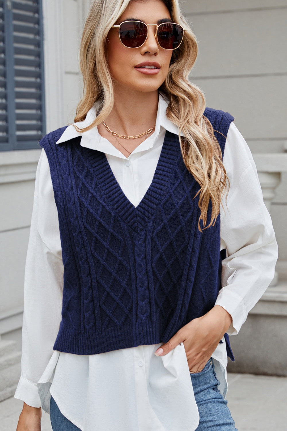 Dark Navy cable knit diamond vest with V-neck, acrylic material, styled over a white shirt.