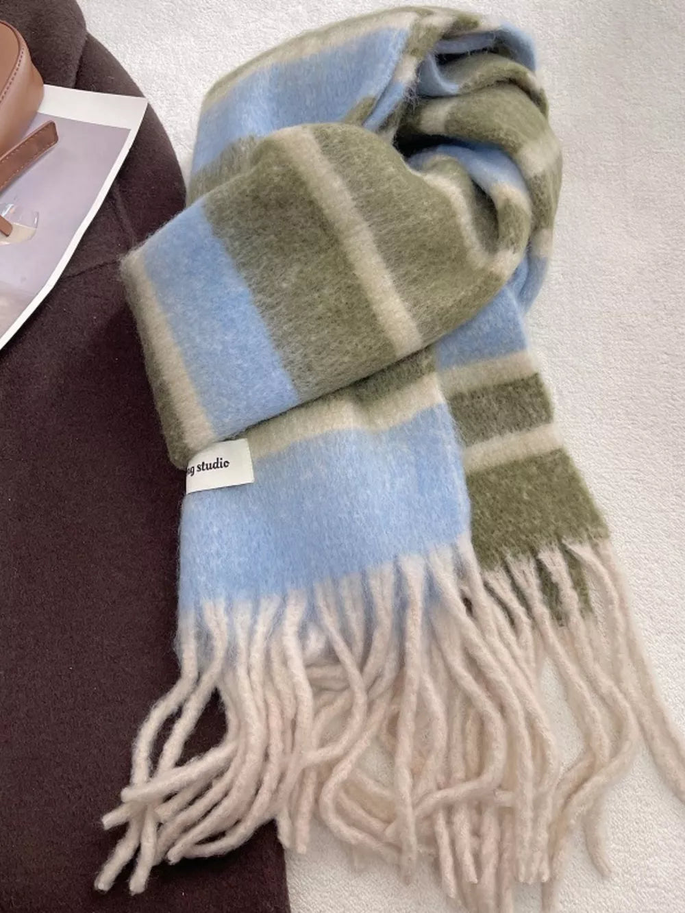Plush striped scarf in blue, green, and cream with cream fringe.