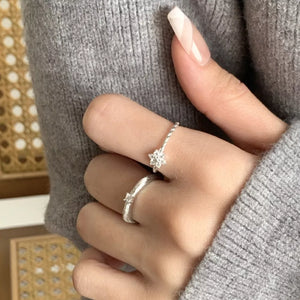 Delicate sterling silver ring with twisted band and zircon flower detail.