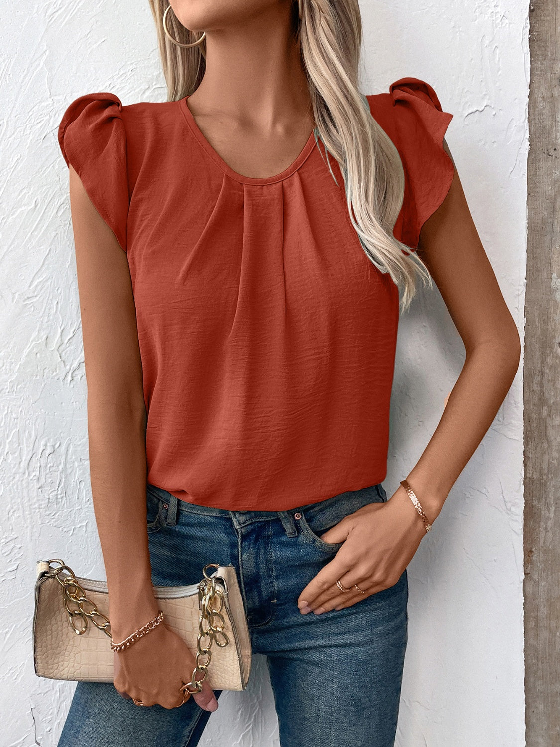 Terracotta pleated yoke flutter sleeve blouse with round neckline.