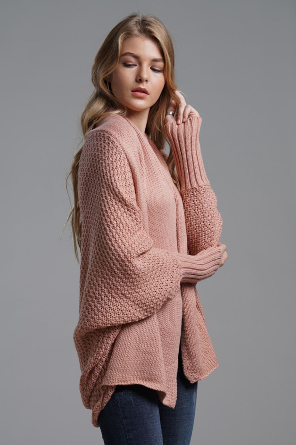 Pink acrylic batwing cardigan with textured knit and wide sleeves.
