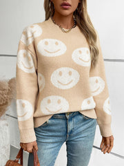 Tan intarsia knit sweater with allover white smiley faces, crewneck, long sleeves.