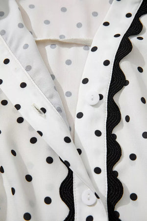 White polka dot midi dress with black scalloped trim and button detail.