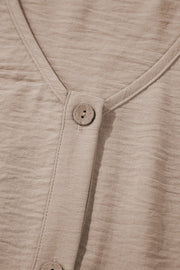 Camel button-front vest detail with textured fabric and wood-look button.
