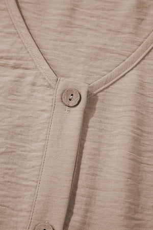 Camel button-front vest detail with textured fabric and wood-look button.