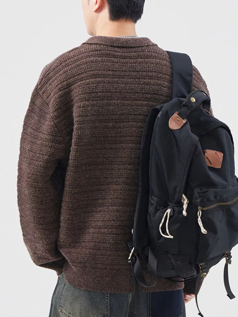 Men's brown ribbed knit cardigan with a collar, styled with a black backpack.