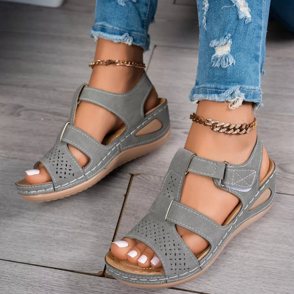 Gray perforated mid-wedge sandals with adjustable straps and white stitching.