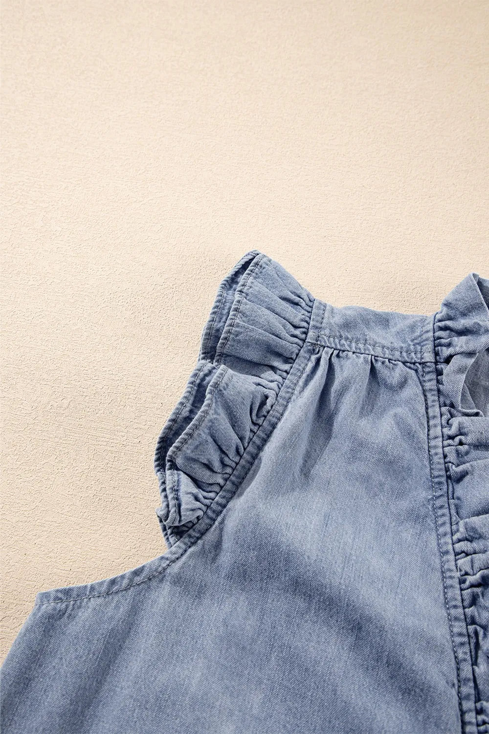 Chambray sleeveless blouse with ruffle trim detail.