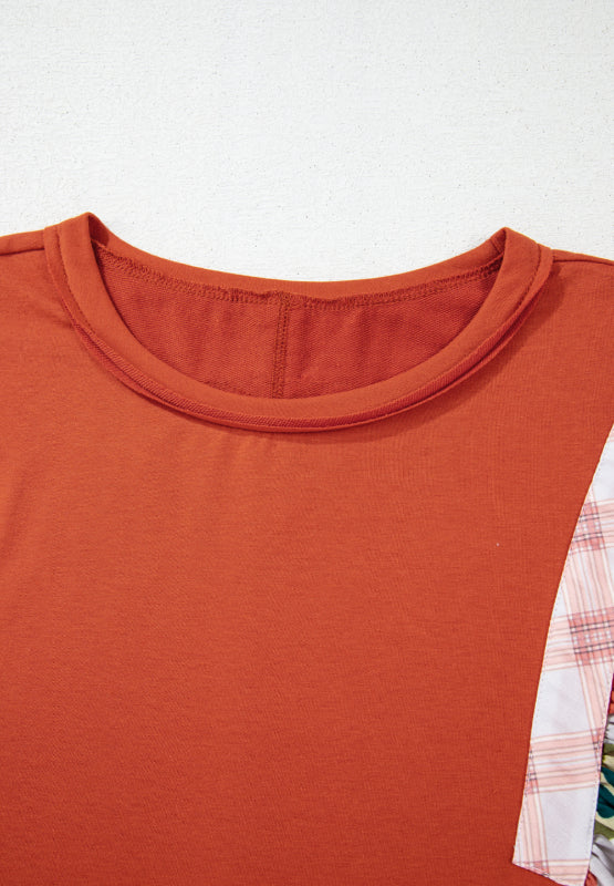 Orange-red blouse with patchwork floral and plaid sleeves and crew neck.