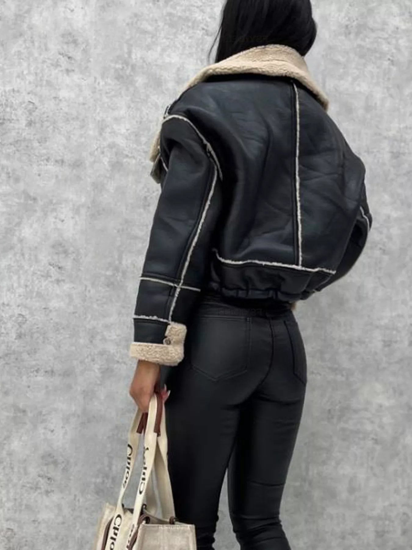 Black cropped sherpa-trim jacket with contrast stitching and shearling collar.
