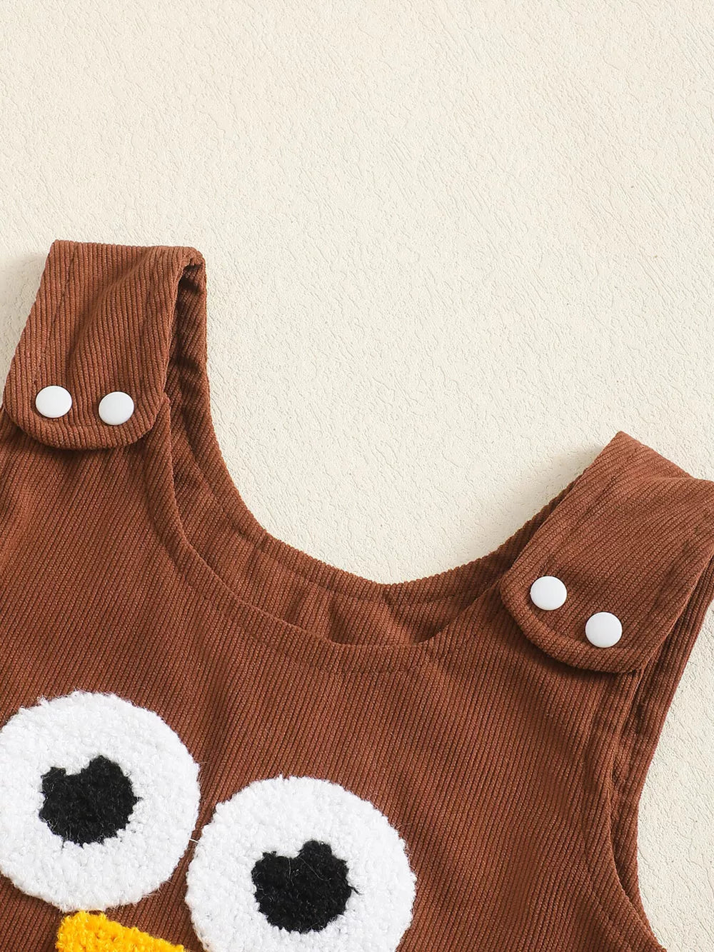 Brown corduroy baby dress with turkey applique and white button straps.