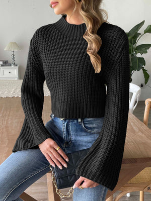 Black ribbed knit crop sweater with bell sleeves and mock neck, styled with jeans.