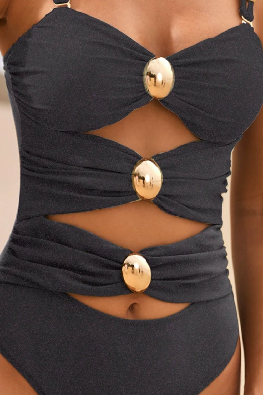 Black one-piece swimsuit with gold button details and cutouts