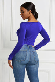 Royal blue long sleeve bodysuit with plunge neckline and zip front, styled with denim jeans.
