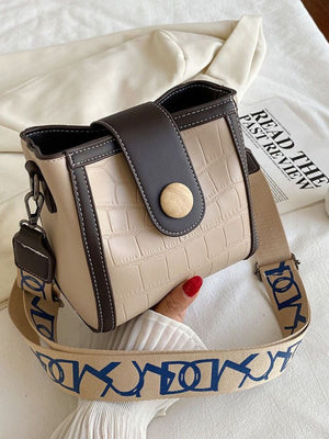 Khaki crocodile pattern mini crossbody bag with contrast trim and wooden button closure.
