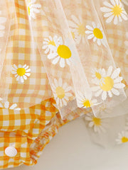 Yellow gingham baby one-piece with daisy-print tulle overlay and ruffle trim.