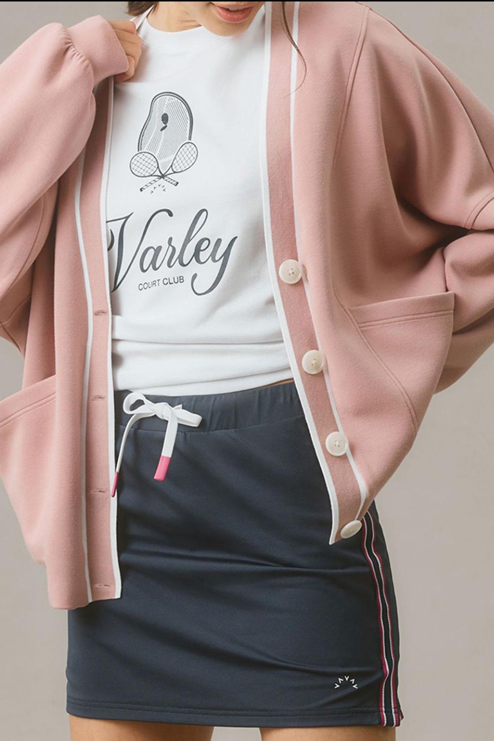 Dusty pink cocoon cardigan with white trim and buttons, styled casually.