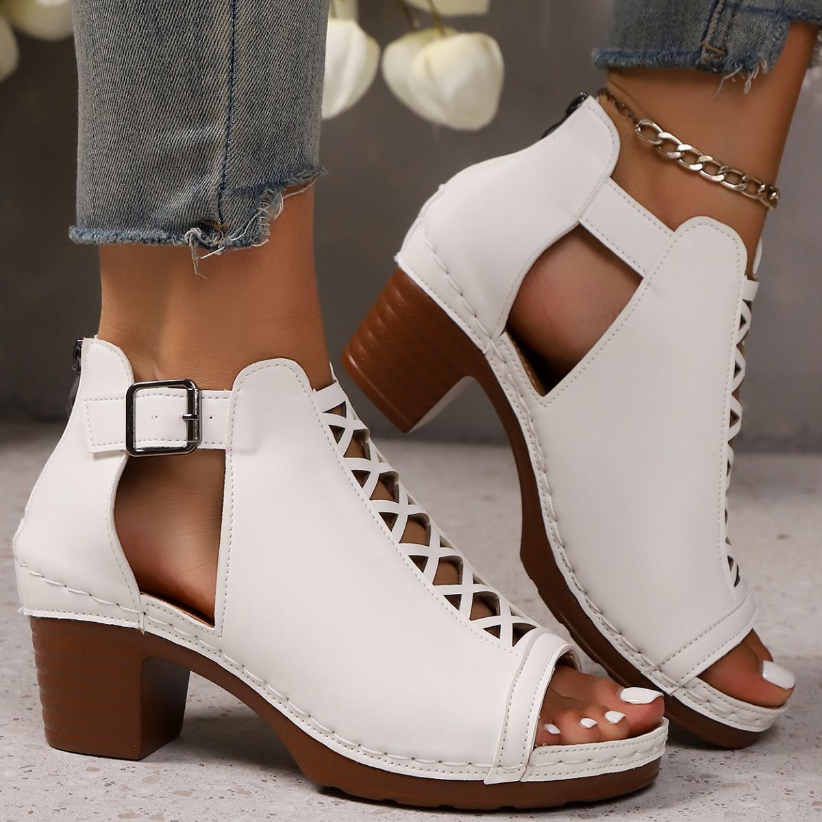 White criss-cross cut-out block heel sandals with ankle strap and buckle detail.
