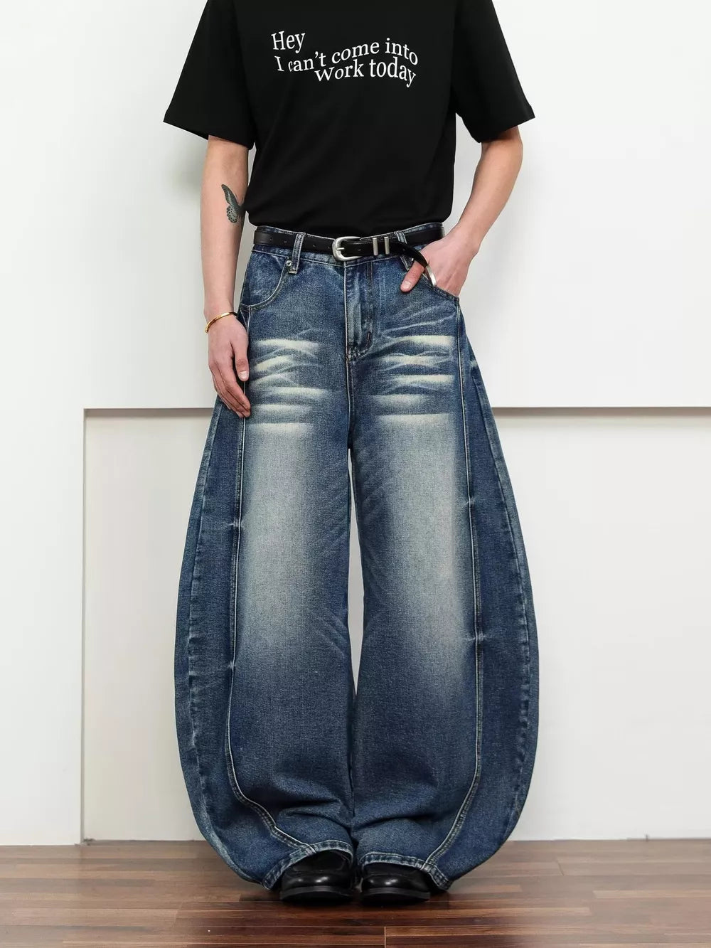Belted wide leg jeans in dark blue denim with a balloon silhouette and distressed details.