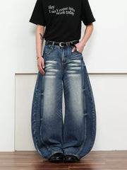 Belted wide leg jeans in dark blue denim with a balloon silhouette and distressed details.
