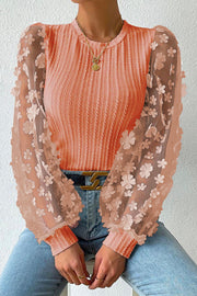 Coral knit top with sheer floral appliqué sleeves and crew neck.