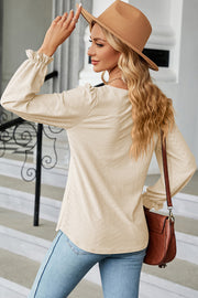 Cream textured puff sleeve blouse with ruffled cuffs, styled with jeans and a hat.