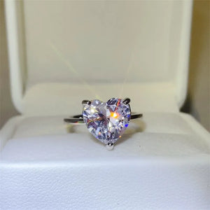 Silver ring with a large, clear heart-cut moissanite solitaire stone.