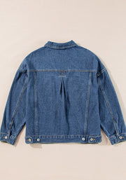 Oversized denim trucker jacket in medium blue with button details and a pleated back yoke.