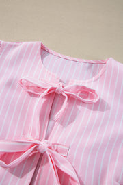 Blush pink striped peplum blouse with bow embellishments at the neckline and waist.