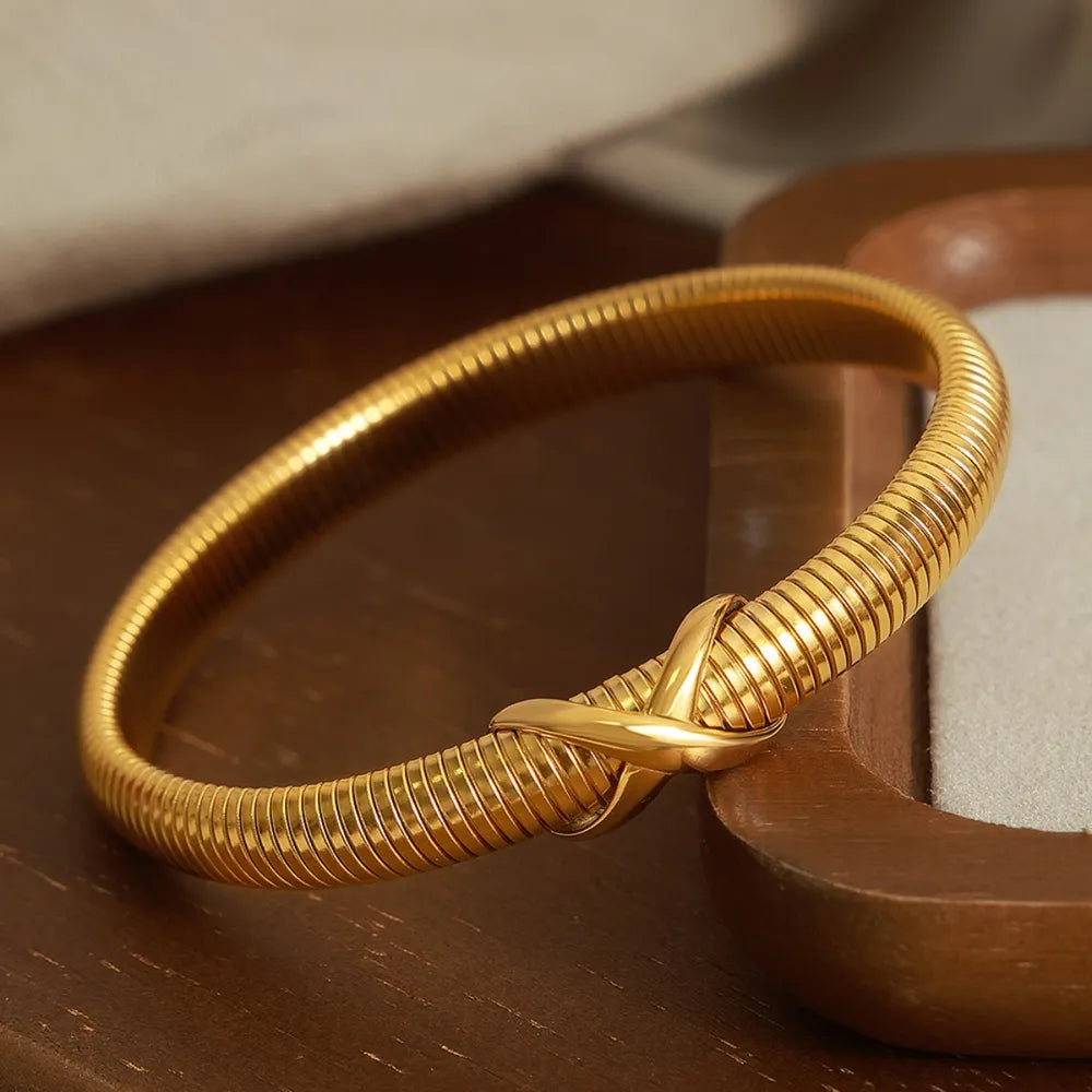 Gold ribbed bangle bracelet with X-detail clasp