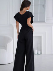 Black wide-leg romper with flutter sleeves and surplice neckline, shown from the back.